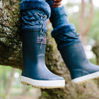 Navy Puddleflex Fleece Lined Wellies being worn whilst sat on a tree branch, close up shot.